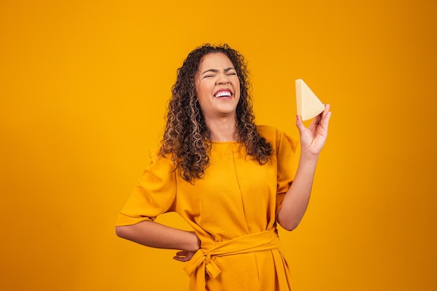 Jovem afro com uma fatia de queijo brie nas mãos. Jovem comendo queijo