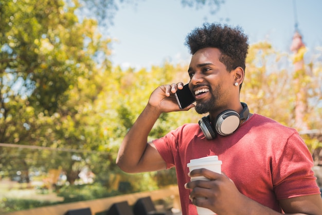 Jovem afro falando ao telefone.