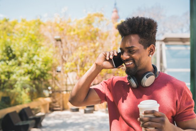 Jovem afro falando ao telefone.