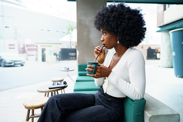 Jovem afro fazendo uma pausa e tomando café no café