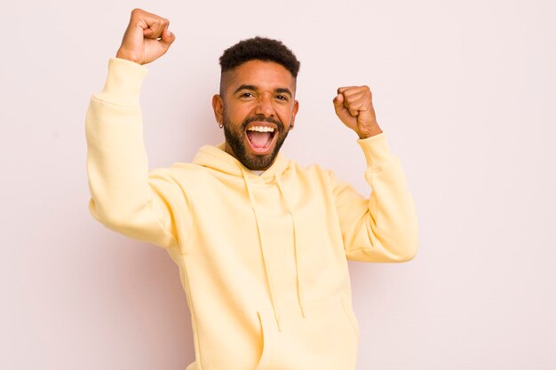 Foto jovem afro gritando triunfante, parecendo animado vencedor feliz e surpreso comemorando