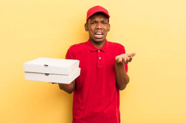 Jovem afro negro olhando desesperado, frustrado e estressado conceito de entregador de pizza