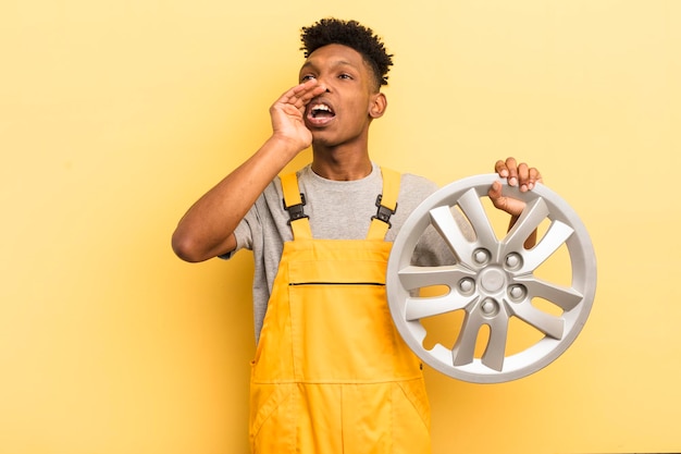 Foto jovem afro negro se sentindo feliz dando um grande grito com as mãos ao lado do conceito de mecânico de carro de boca