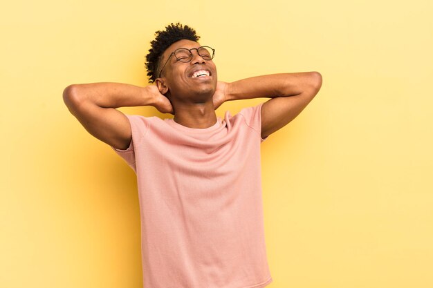 Jovem afro negro sorrindo e se sentindo relaxado satisfeito e despreocupado rindo positivamente e arrepiando