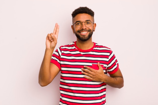 Jovem afro olhando feliz confiante e confiável sorrindo e mostrando sinal de vitória com uma atitude positiva