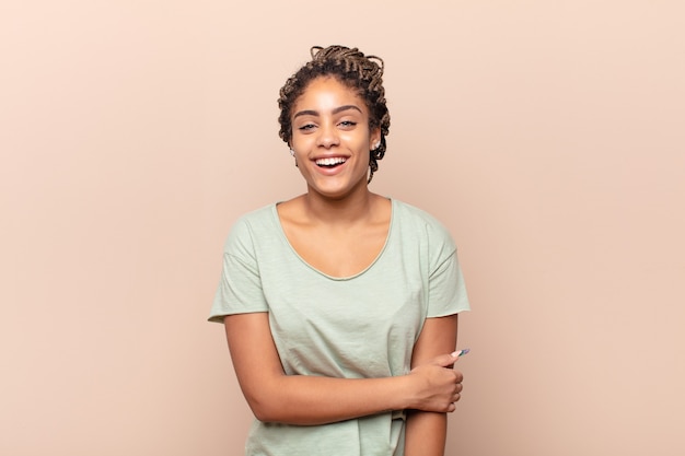 jovem afro rindo tímida e alegre, com uma atitude amistosa e positiva, mas insegura