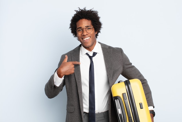 Jovem afro se sentindo feliz, surpreso e orgulhoso, apontando para si mesmo com um olhar empolgado e surpreso