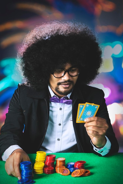 Jovem afro segura cartas de pôquer no cassino