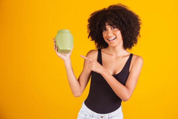 Foto jovem afro segurando nas mãos um pacote de creme de cabelo