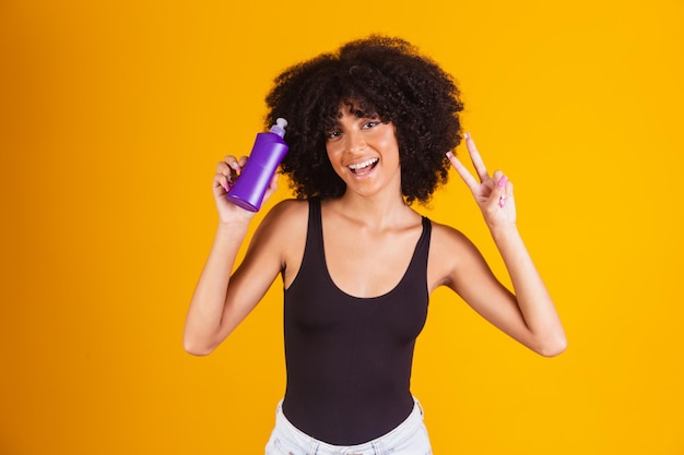 Jovem afro segurando nas mãos um pacote de creme de cabelo