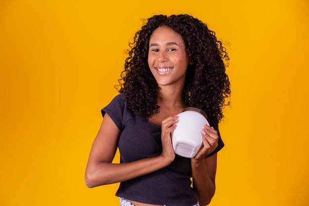 Jovem afro segurando nas mãos um pacote de creme de cabelo