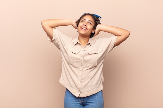 Jovem afro sorrindo e se sentindo relaxada, satisfeita e isolada