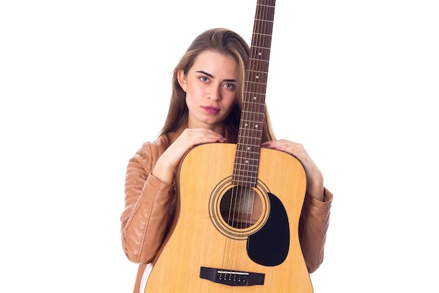 Jovem agradável de jaqueta marrom segurando uma guitarra em fundo branco no estúdio