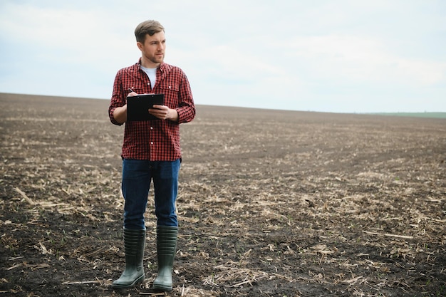 Jovem agricultor em um campo de semeadura controlada de milho