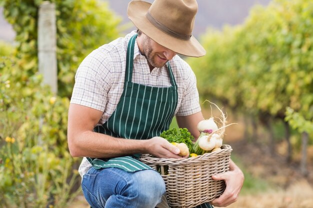 Jovem agricultor feliz segurando uma cesta de legumes