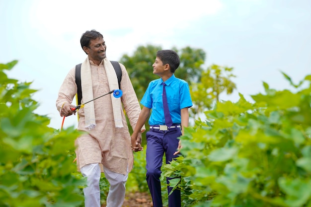 Jovem agricultor indiano com seu filho no campo de agricultura verde.