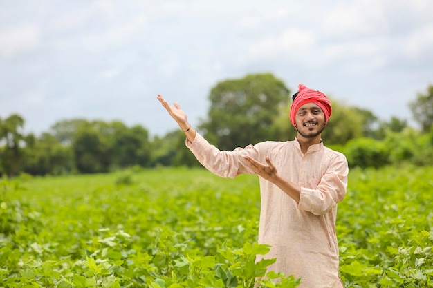 Jovem agricultor indiano em pé no campo de agricultura.