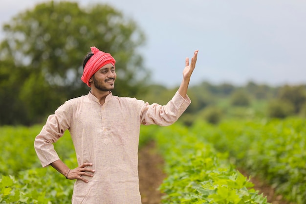 Jovem agricultor indiano em pé no campo de agricultura.