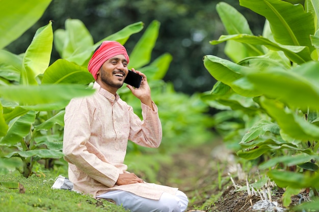 Jovem agricultor indiano falando em smartphone no campo de agricultura de banana.