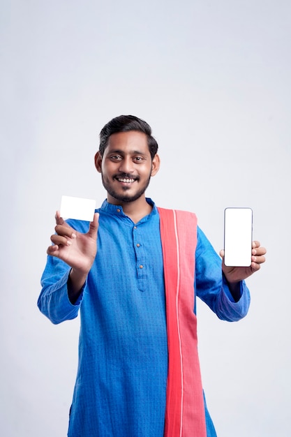 Jovem agricultor indiano mostrando cartão e smartphone em fundo branco.