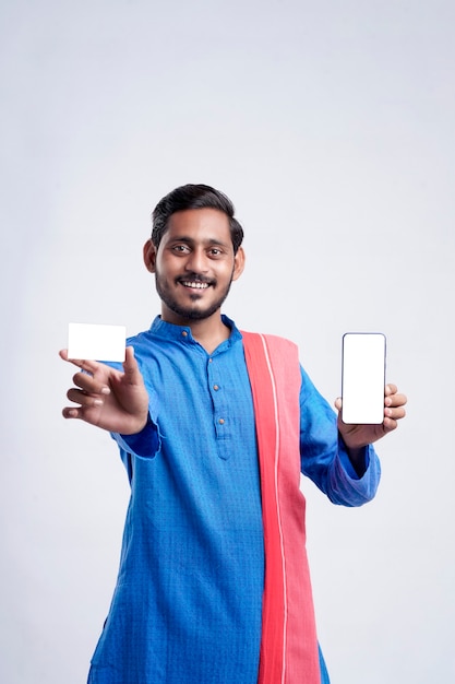 Jovem agricultor indiano mostrando cartão e smartphone em fundo branco.