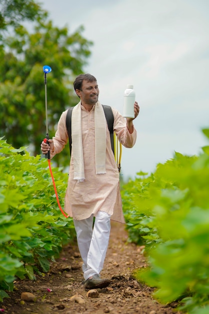 Jovem agricultor indiano mostrando o frasco de fertilizante líquido no campo de agricultura.