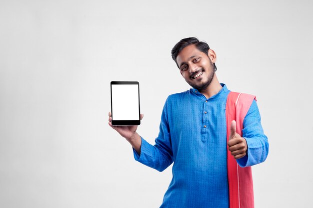 Jovem agricultor indiano mostrando o tablet e dando expressão em fundo branco.