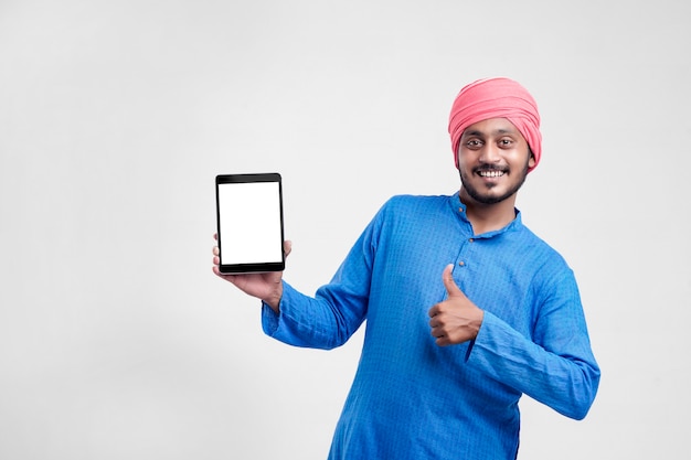 Jovem agricultor indiano mostrando o tablet e dando expressão em fundo branco.