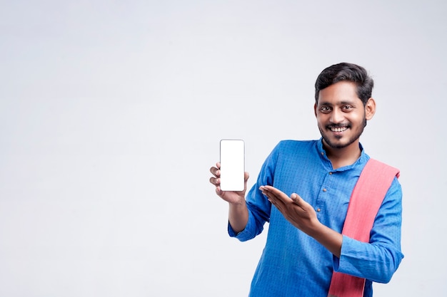 Jovem agricultor indiano mostrando smartphone e dando expressão em fundo branco.