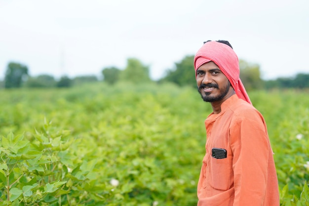 Jovem agricultor indiano no campo de agricultura de algodão