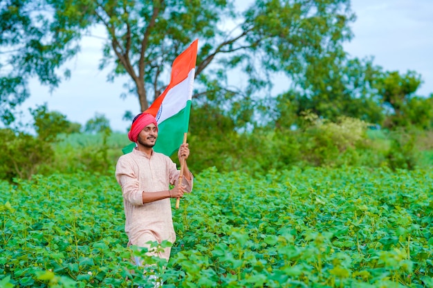 Jovem agricultor indiano segurando bandeira indiana em campo de agricultura