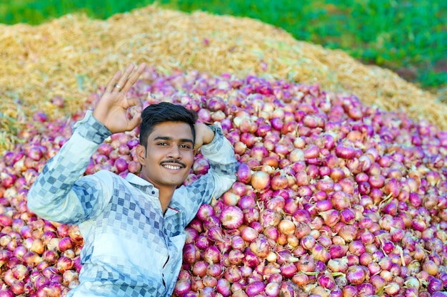 Jovem agricultor indiano segurando uma cebola em um campo de agricultura