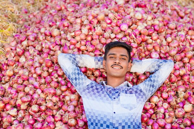 Jovem agricultor indiano segurando uma cebola em um campo de agricultura