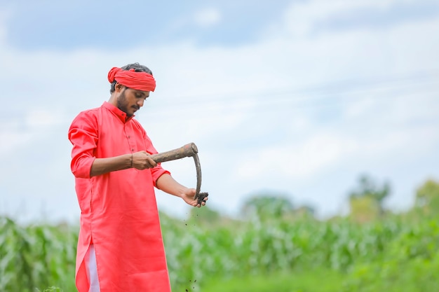 Jovem agricultor indiano trabalhando arduamente com equipamentos agrícolas em seu campo