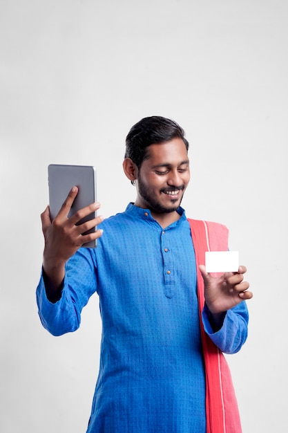 Jovem agricultor indiano usando tablet e dando expressão em fundo branco.