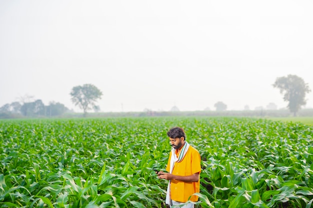 Jovem agricultor indiano usando um telefone inteligente