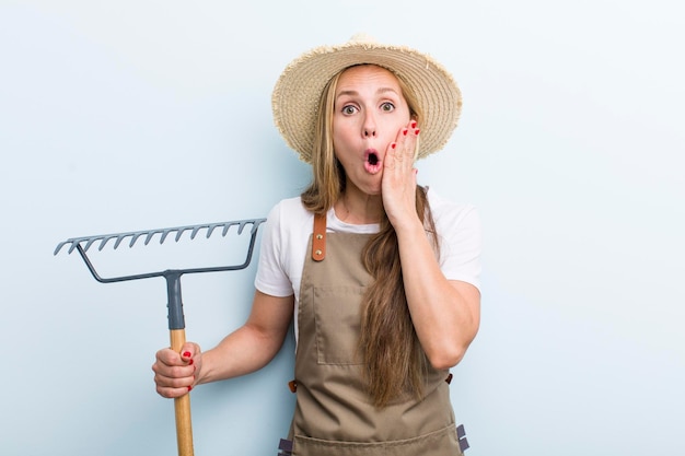 Jovem agricultora loira adulta com um ancinho