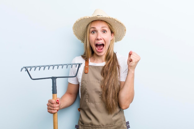 Jovem agricultora loira adulta com um ancinho