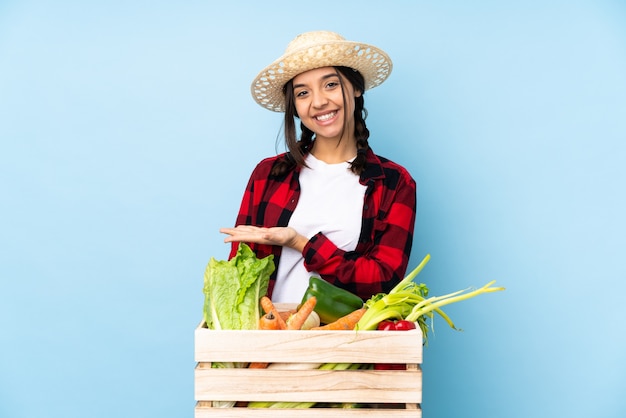 Jovem agricultora Mulher segurando legumes frescos em uma cesta de madeira