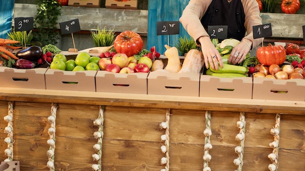 Jovem agricultora organizando produtos agrícolas em caixas, colocando frutas e legumes no estande no mercado de agricultores locais. Titular de barraca de mulher vendendo produtos caseiros. Fechar-se.