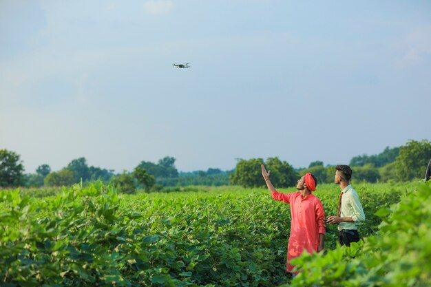 Jovem agrônomo e fazendeiro indiano usando drone para verificação no campo agrícola