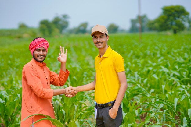 Jovem agrônomo ou banqueiro indiano aperta a mão de um fazendeiro no campo de agricultura.