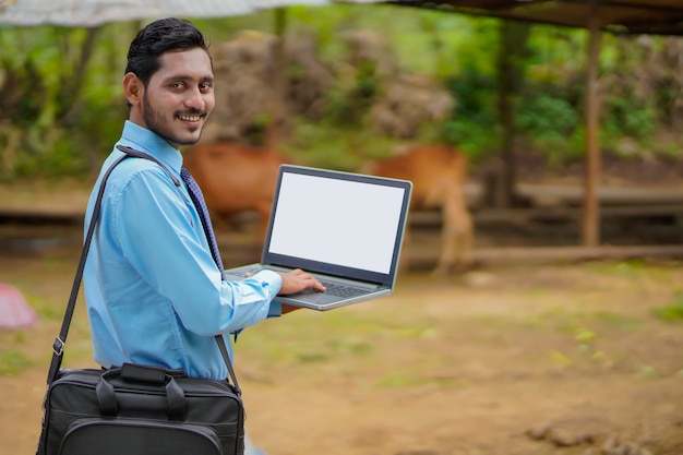 Jovem agrônomo ou banqueiro indiano mostrando a tela do laptop