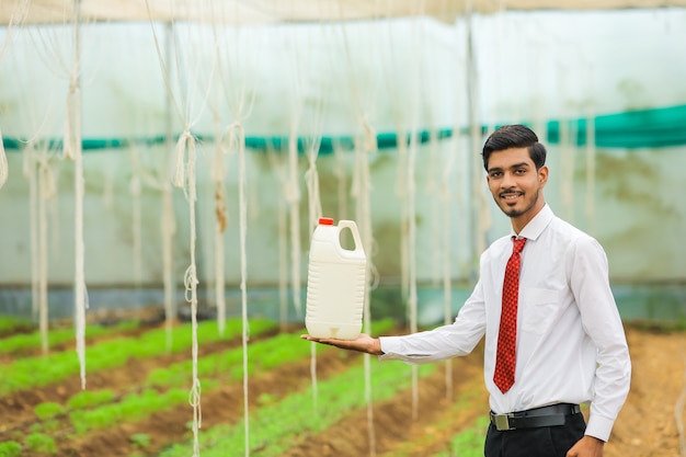 Jovem agrônomo segurando uma garrafa na mão na estufa