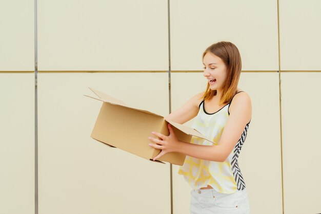 Foto jovem alegre abrindo uma caixa de papelão