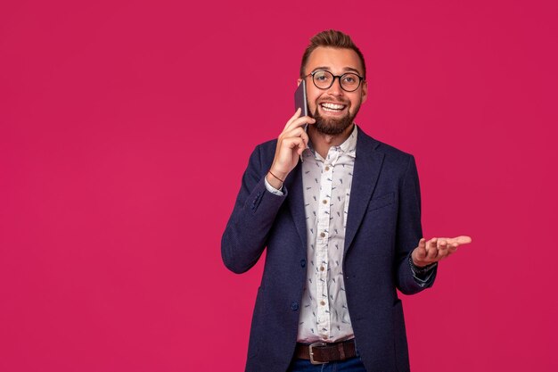 Jovem alegre advogado ou empresário está de pé no fundo rosa e sorrindo, falando no p.