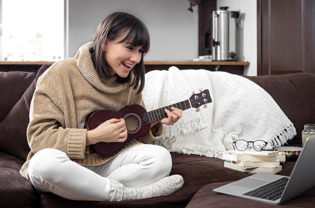 Jovem alegre aprendendo a tocar ukulele. conceito de educação online, educação em casa.