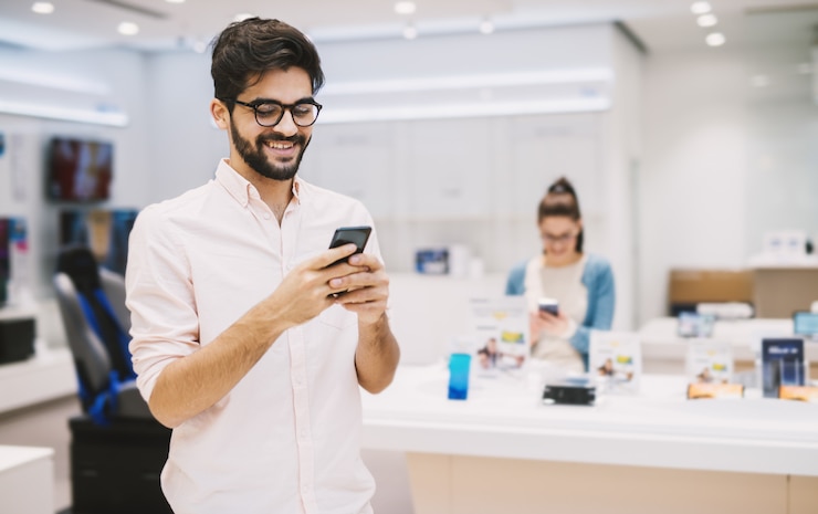 Foto jovem alegre bonito verificando um telefone móvel
