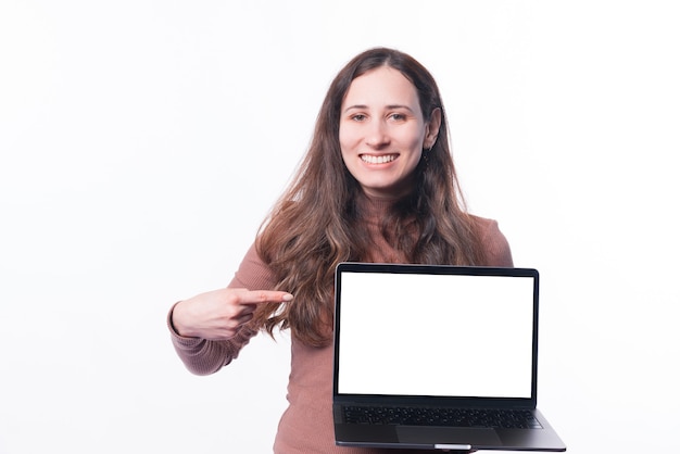 Foto jovem alegre casual apontando para uma tela em branco no laptop e sorrindo