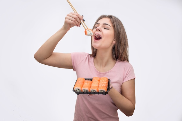 Jovem alegre coloca um pedaço de sushi na boca